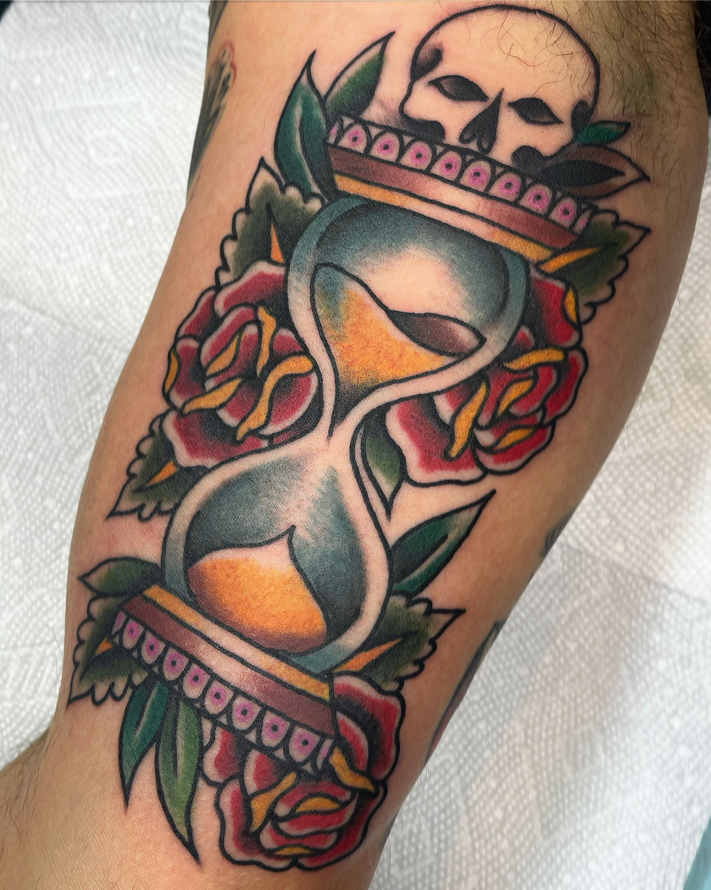 a tattoo of a hourglass with roses and a skull