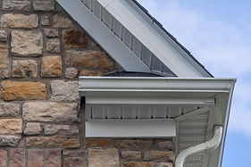 Gable with colored stone siding, white frame gutter guard system, fascia, drip edge, soffi