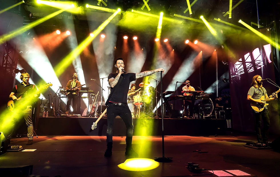 Maroon 5 performing live at the Airbnb Open Spotlight concert in downtown Los Angeles as Adam Levine sings on stage under concert lighting