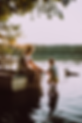 Image of woman and young child in and around a boat on a lake with a dog swimming nearby.