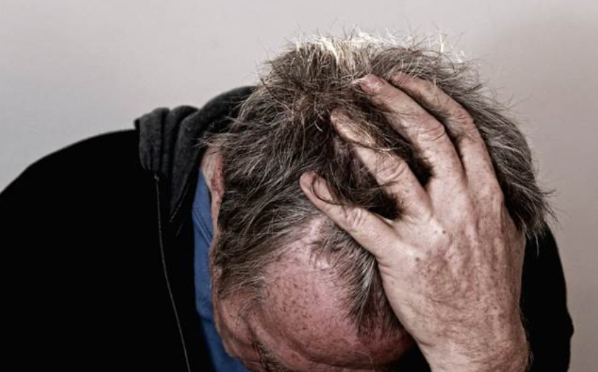 Image of man holding his head in his hand