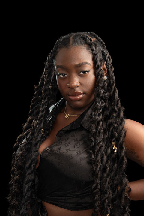 Cinematic studio portrait of young Black woman with long braided hair wearing black top, photographed in Rahway NJ.