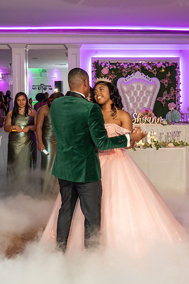 Couple dancing at a formal celebration as purple uplighting and low-lying fog frame the dance floor.