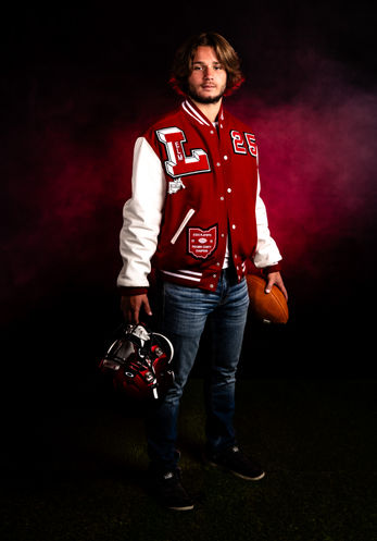 Senior portrait of a young man wearing a varsity jacket, holding a football and helmet, showcasing E3 Photography’s senior portraits in Ohio.