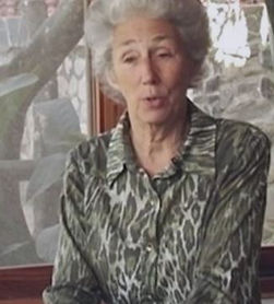 An older Susan with short white hair, talking, wearing a forest-green leopard print blouse