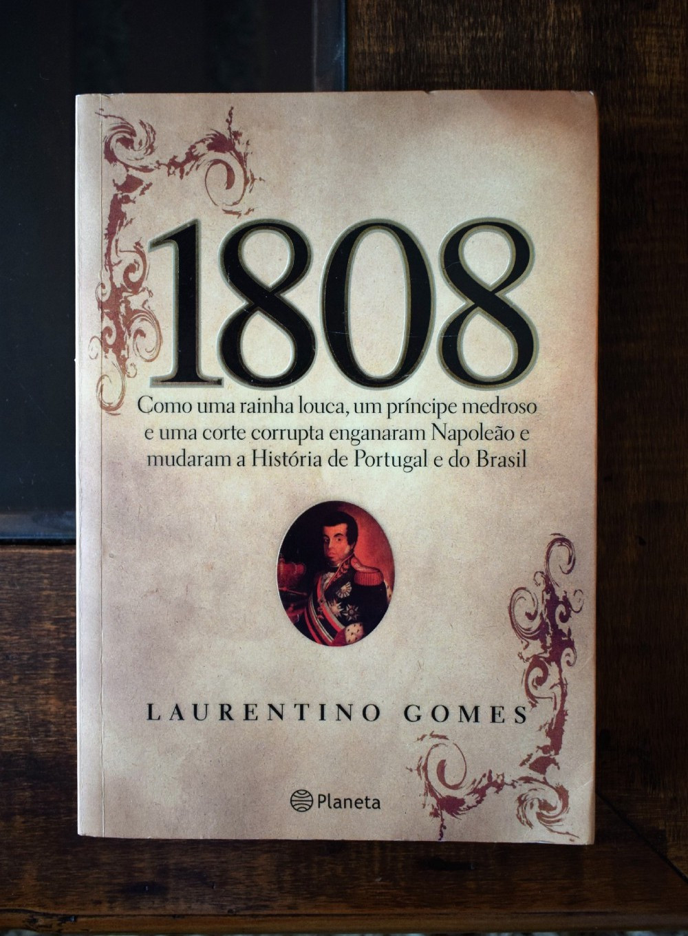 O livro 1808, de Laurentino Gomes, em uma mesa de madeira.