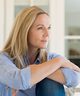 Woman with arms around her knees, looking ahead