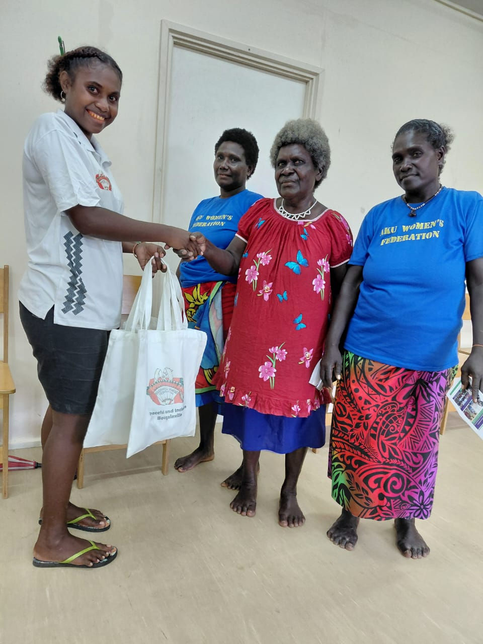 BWF Young Women Officer Ms. Valencia Golu presenting the BWF Merchandise products to Aku Women's Association President Maria Pariai at the Baubake Community Government Hall upon receiving their registration.