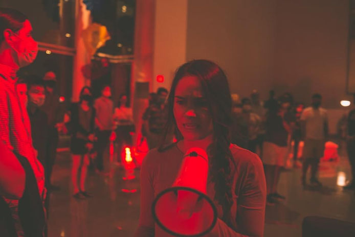 A person with long hair speaks into a megaphone.