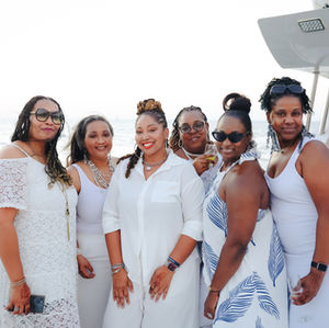 Group of Black friends dressed in white enjoying Dubai views from a private yacht"