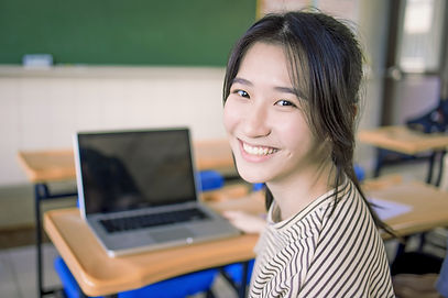 Smiling Student Sitting At Desk_edited.j