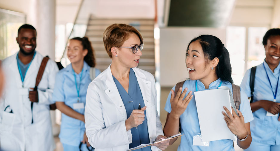 nurses walking and conversing in a hallway.