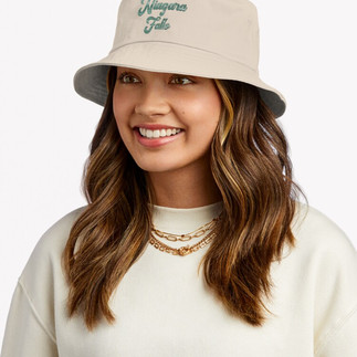 Girl wearing Bucket hat in tan color with the Word Niagara Falls in emerald green, the color of the Niagara River