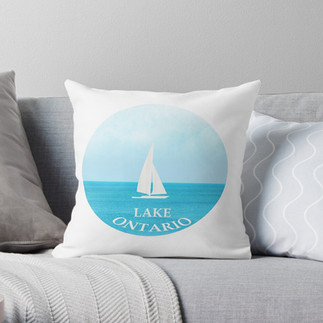 Throw pillow with a round circle in blue and a white sailboat with Lake Ontario in white letters