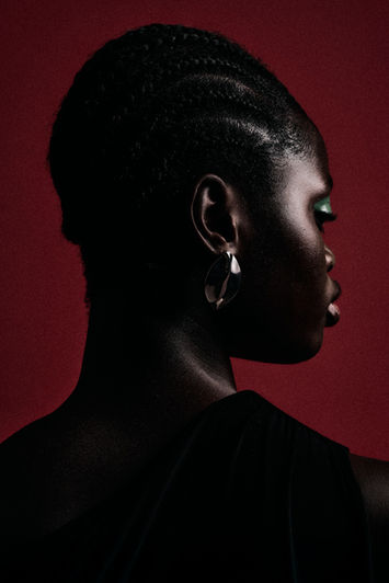 Dramatic fashion editorial photo of a black model side lit in a black dress
