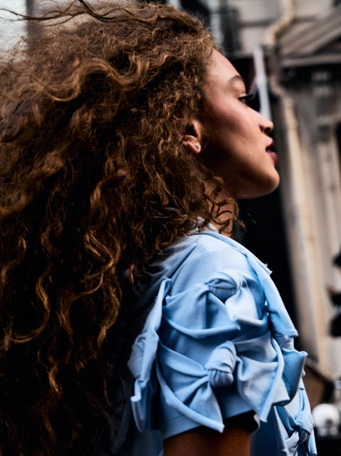 A close up photo of a model  walking by in a blue dress outside of the ACNE show at Paris Fashion Week SS26