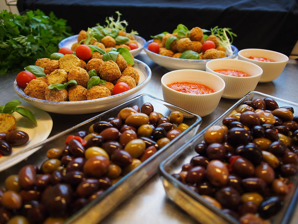 Buffet dâantipasti: boulettes dorĂ©es, tomates cerises, basilic, sauces rouges et olives variĂ©es sur table inox.