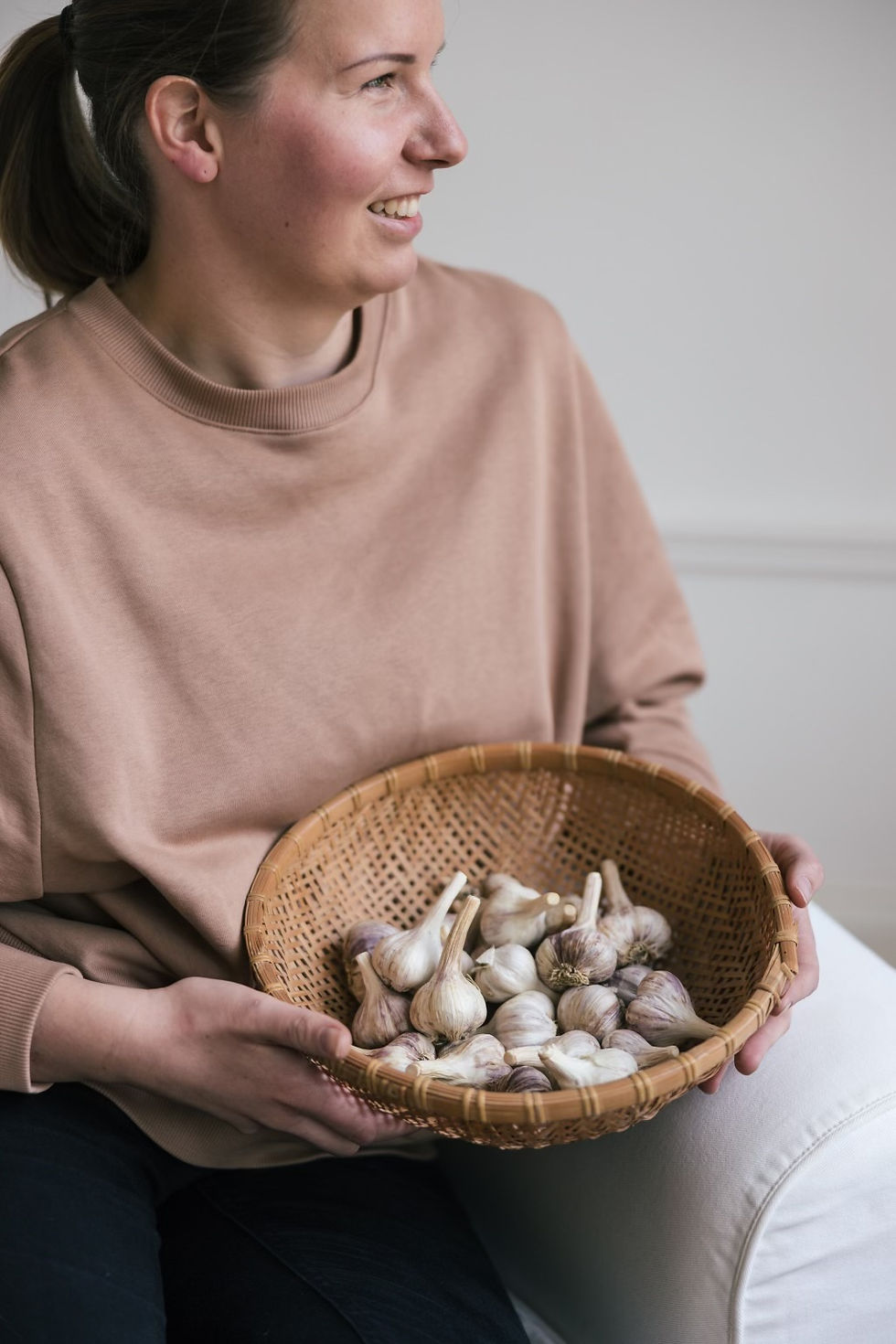 Hanna pitelee käsissään koriin kerättyä Uusitalon tilan valkosipulisatoa Lohjansaaressa.