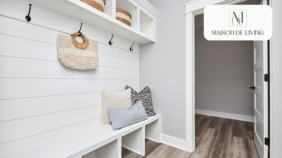 Modern mudroom with white walls, hooks, a woven bag, and cushions. Shelves hold baskets. Door leads to a gray hallway. Calm and neat.
