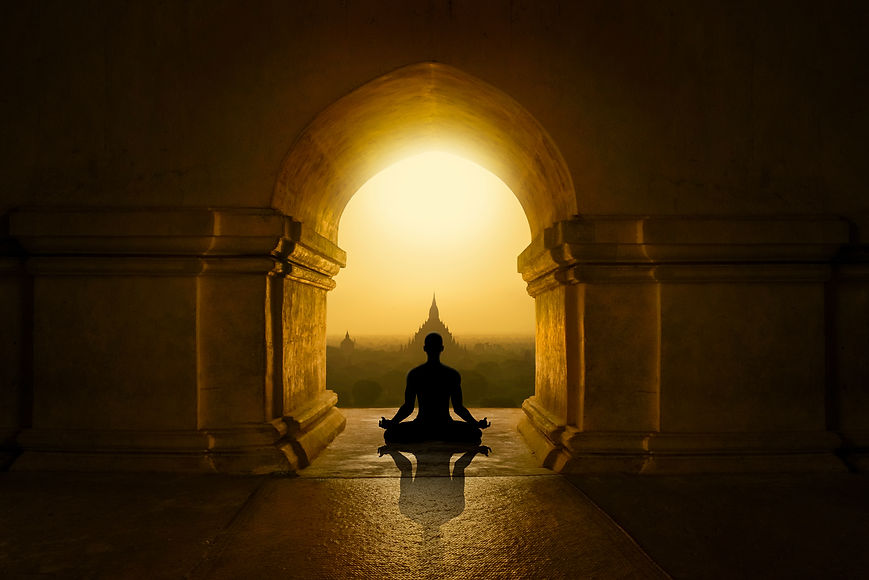 Silhouette assise en méditation de dos devant un temple au lever du soleil, illustrant la puissance artistique du yoga
