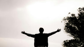 Homme de dos debout sur un promontoire, surplombant une vallée noyée dans les nuages, symbole du dépassement de la peur et de l’éveil de l’artiste intérieur.