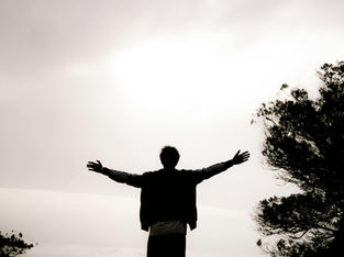 Homme de dos debout sur un promontoire, surplombant une vallée noyée dans les nuages, symbole du dépassement de la peur et de l’éveil de l’artiste intérieur.