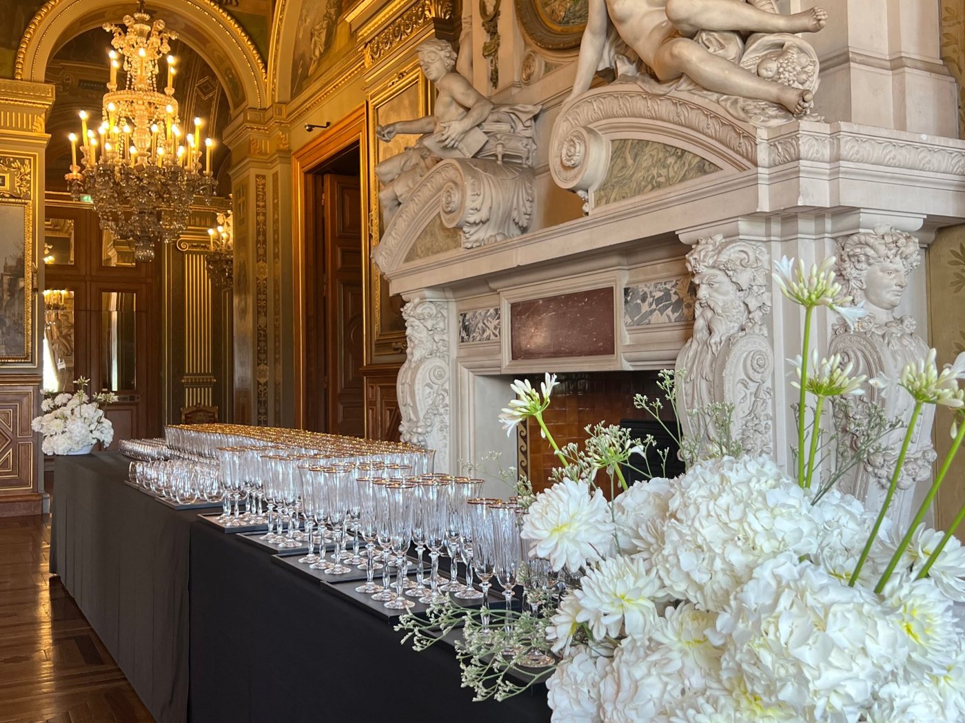 Cocktail dressé au pied d’une cheminée sculptée, sous les dorures et les lustres de l’Hôtel de Ville de Paris