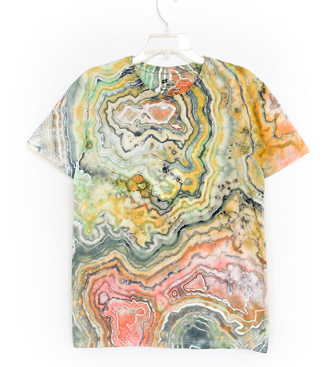 A shirt hanging on a white wall that is dyed in the geode tie dye style. 