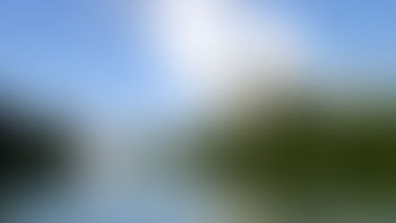 Centrale nucléaire du Bugey au bord du Rhône, avec plusieurs tours de refroidissement rejetant de la vapeur d’eau, entourée de végétation.