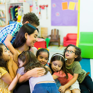 Lovely beautiful preschool teacher hugging her kindergarten students and enjoying coming b