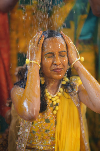 Bride enjoying haldi ceremony surrounded by family and friends