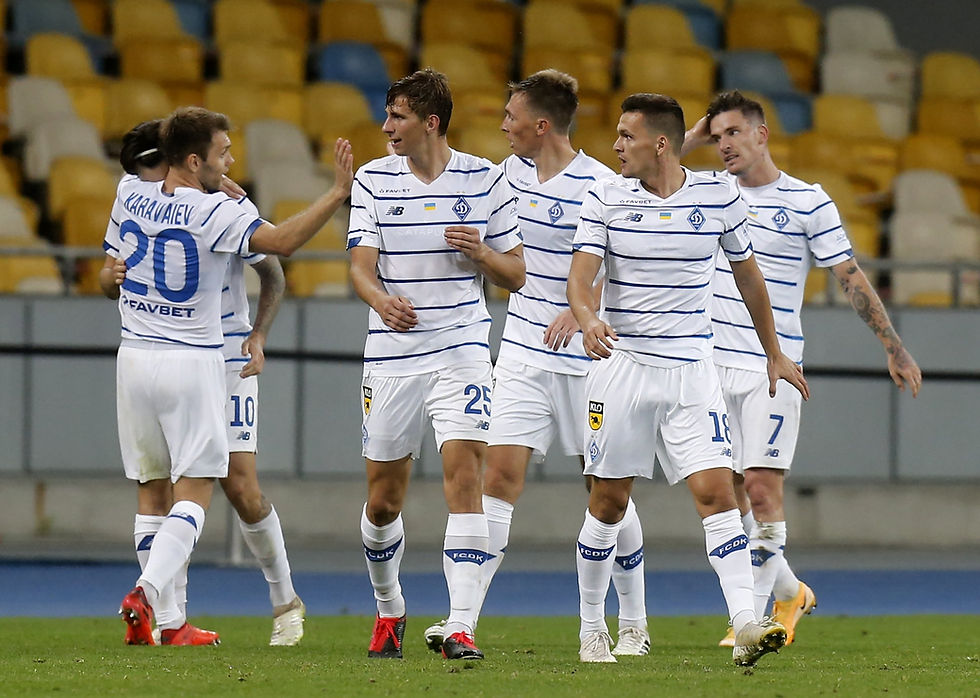 Soccer players in white striped jerseys celebrate on a field with a yellow and blue stadium background. The mood is joyful.