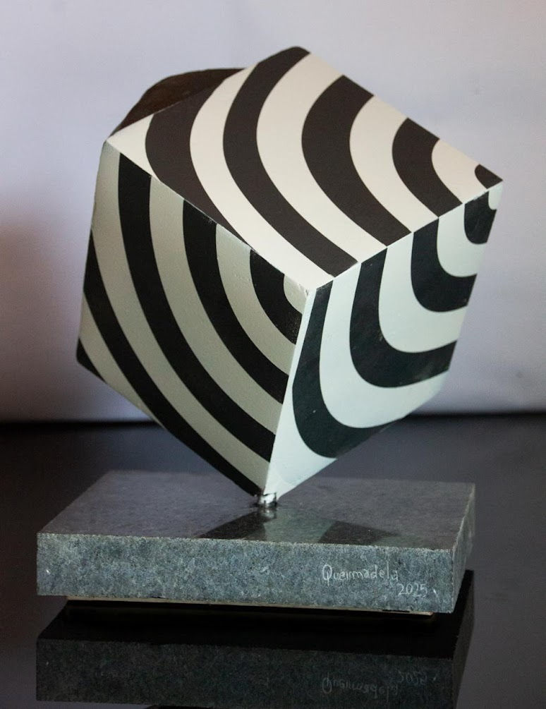 Miniaturbild: Escultura abstrata preta e branca com padrões espirais sobre base escura.