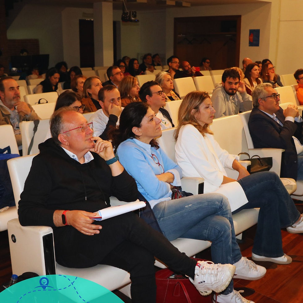 L'immagine mostra un gruppo di persone sedute in una sala conferenze, con l'attenzione rivolta verso un punto fuori dalla vista dell'immagine, presumibilmente un relatore o uno schermo. Il pubblico è variegato, con uomini e donne di diverse età che sembrano professionisti o partecipanti a un evento formativo o a un seminario. Alcuni tengono in mano penne e quaderni, suggerendo che potrebbero essere impegnati a prendere appunti o a seguire una presentazione. L'atmosfera è di concentrazione e interesse, e la sala ha un'illuminazione vivace e calda.