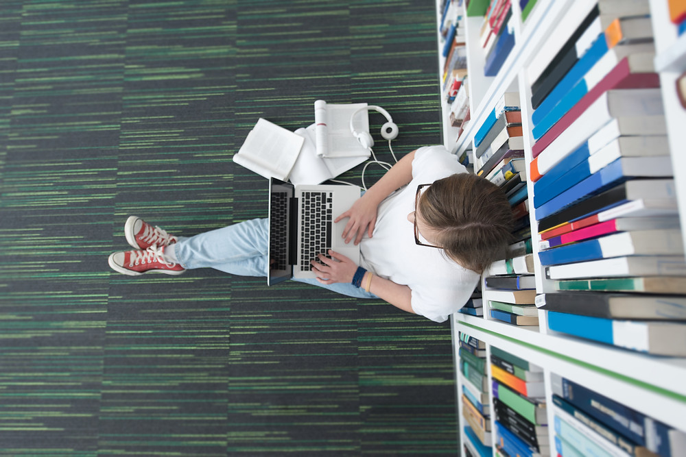 teen using laptop in library