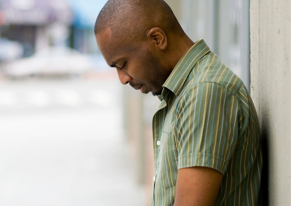 A man leaning against a wall looking upset