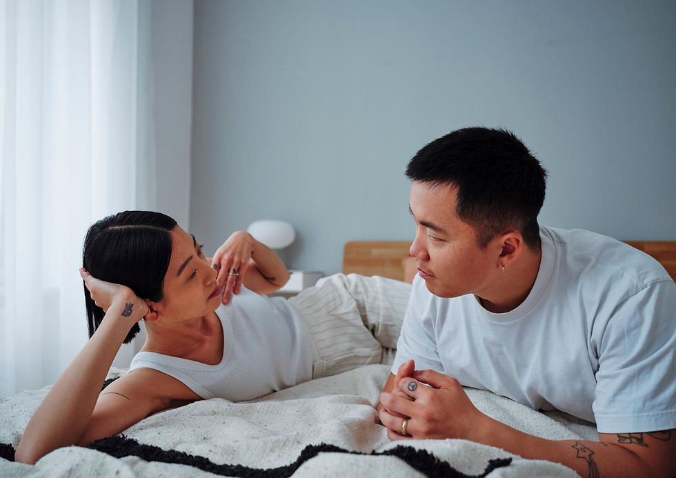 Autistic adult lying in bed with partner, engaged in calm conversation; image reflects that all experiences are valid, and connection is possible despite differences.