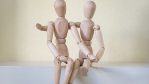 Two wooden dolls represent an autistic couple sharing a gentle, supportive moment together.