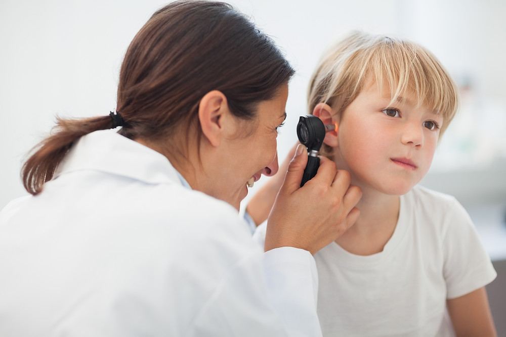 An Audiologist looks into a boys ear