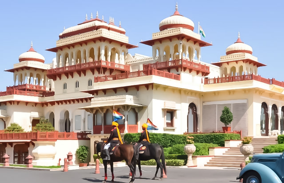 Majestic view of Rambagh Palace, with two traditionally dressed guards on horseback.