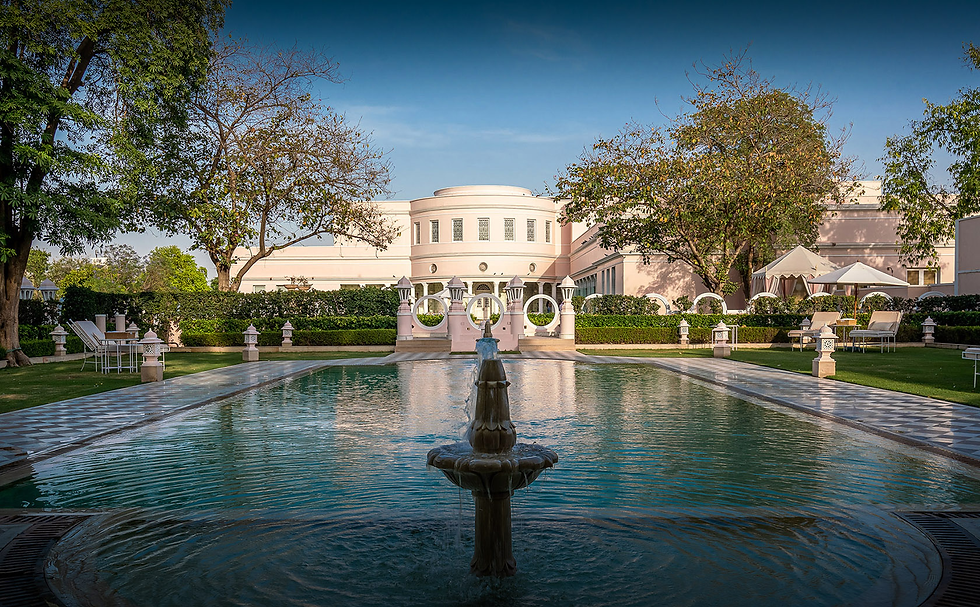 The serene courtyard of Rajmahal Palace, featuring a central fountain, lush greenery, and elegant architecture.