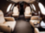 Luxurious interior of a private jet, featuring plush leather seating and elegant wood paneling.