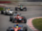 High-speed racing action as drivers navigate a tight corner during the Grand Prix.