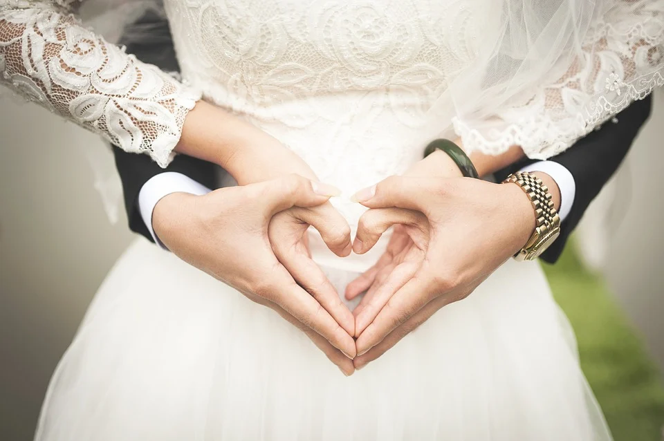 Bride and groom holding hands in a heart shape