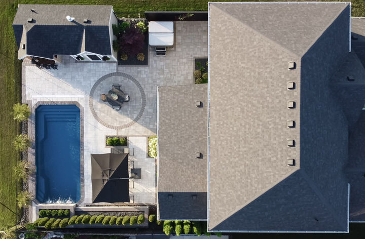 Straight down view from taken with a drone of a beautiful backyard fully landscaped with a fiberglass pool house, patio and gardens