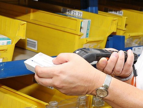 Frau hält Scangerät und scant damit eine Verpackung.