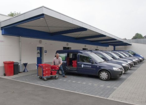 Ein Mann packt Behälter in eines der vielen Fahrzeuge auf dem neuen Betriebsgelände. 