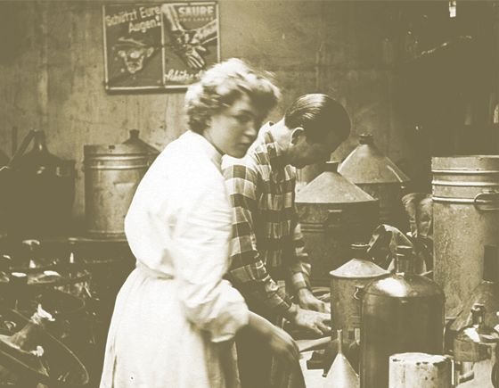 altes Foto von einer Frau mit kurzen Haaren und einem Mann, die in eine Raum arbeiten.