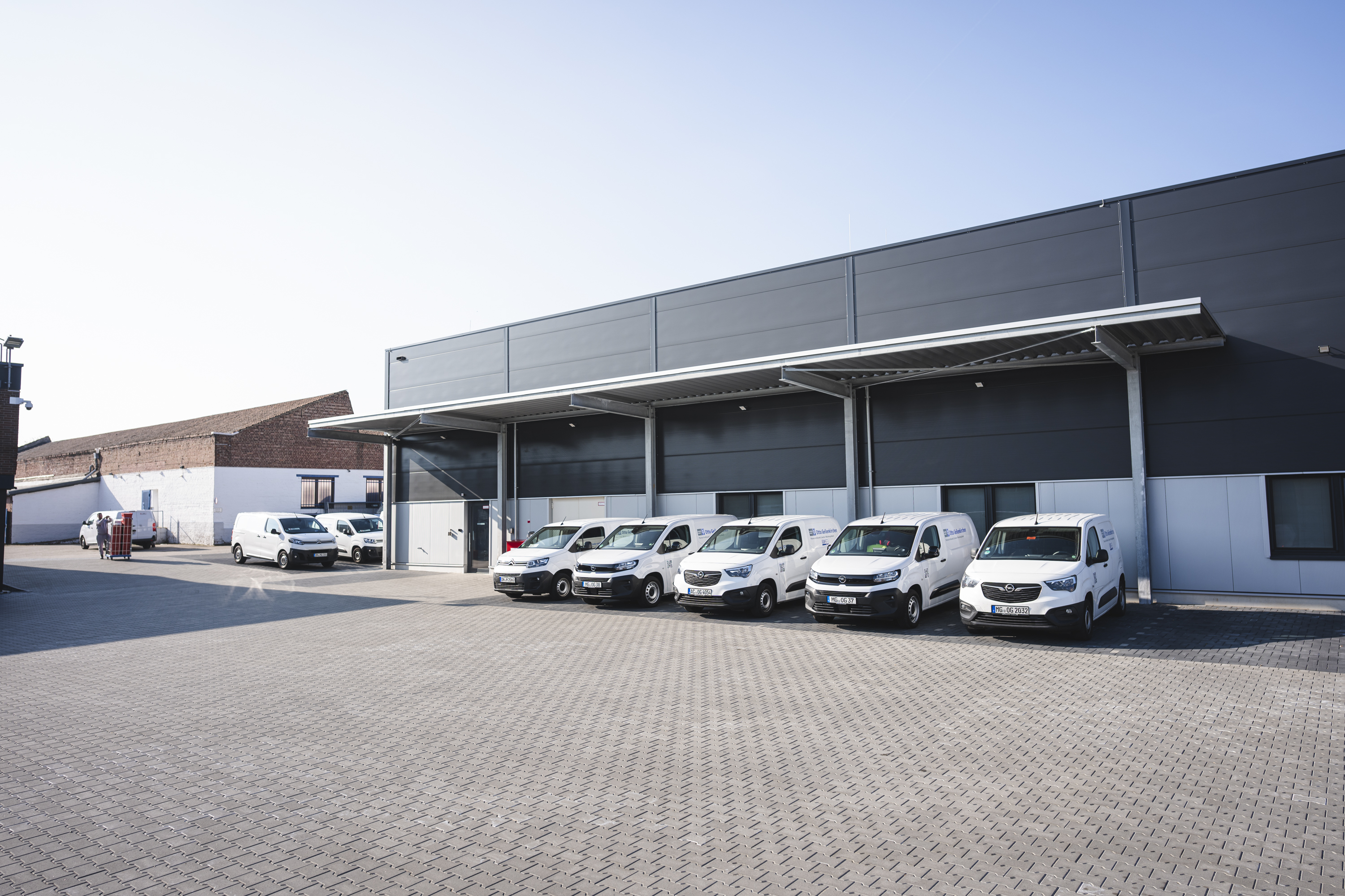 Mehrere weiße Transporter von Otto Geilenkirchen stehen auf einem neuen Grundstück.