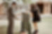 man in a grey suit and a woman in a short black dress laugh ans they play giant connect 4, the girl is putting the first orange disc in
